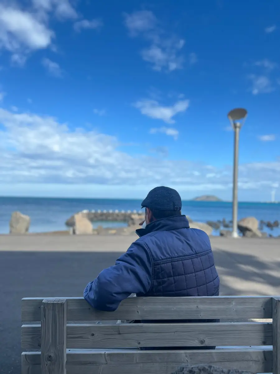 A person sitting on a bench and looking out to sea near Panpo Port