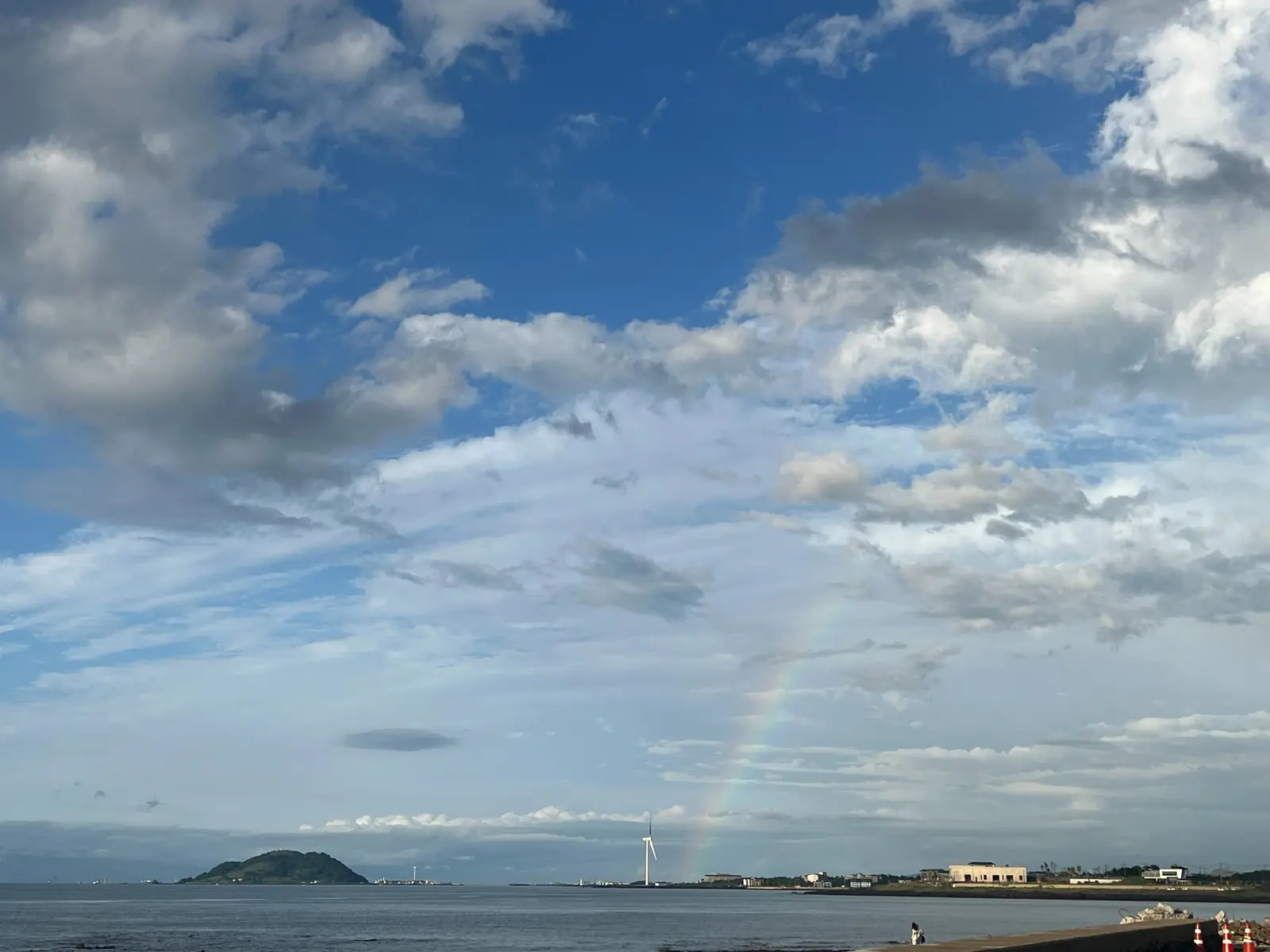 A rainbow above the coast and wind turbines near Panpo Port