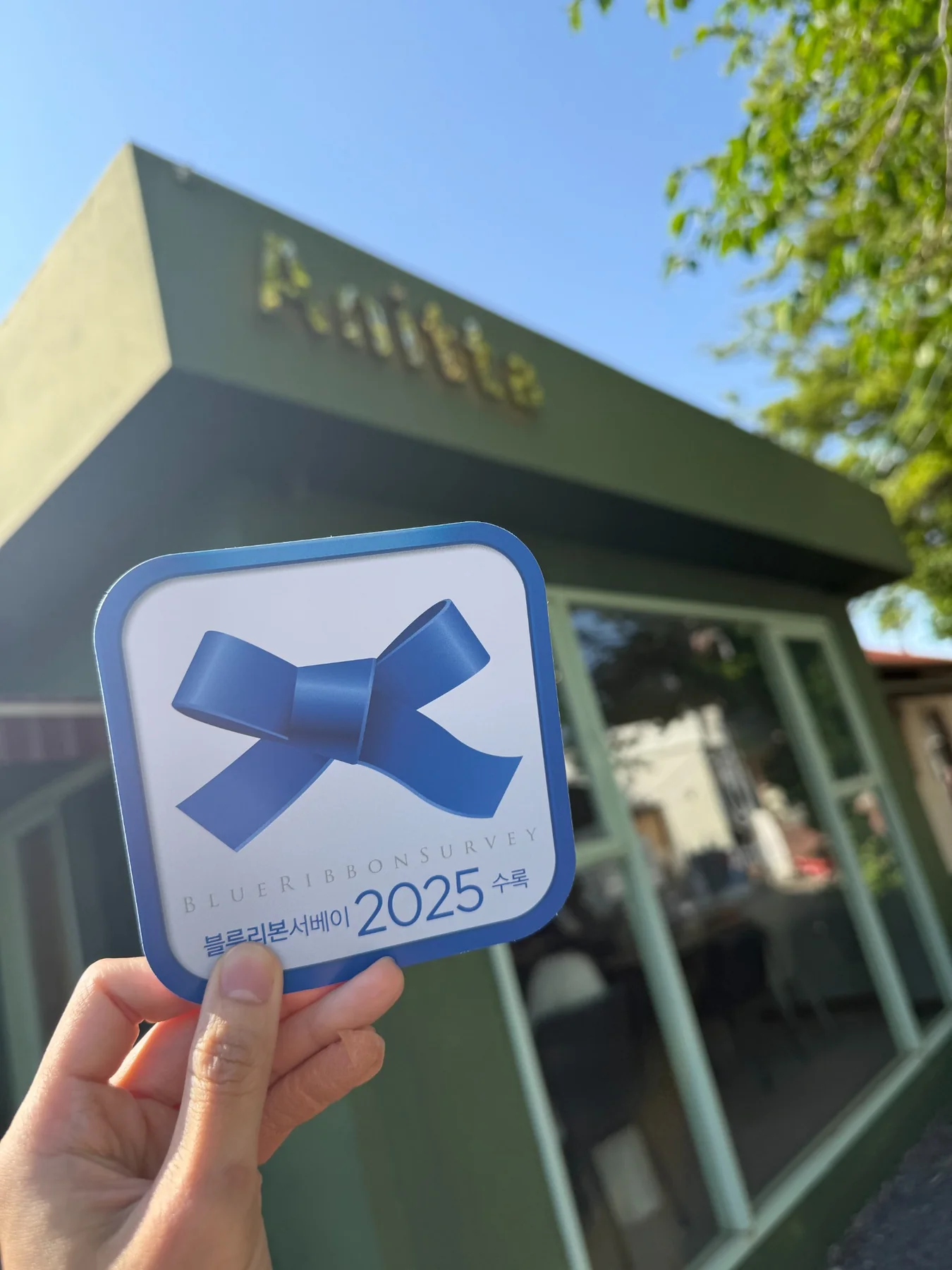 아니따 초록색 외관 앞에서 확인한 2025 블루리본 서베이 스티커