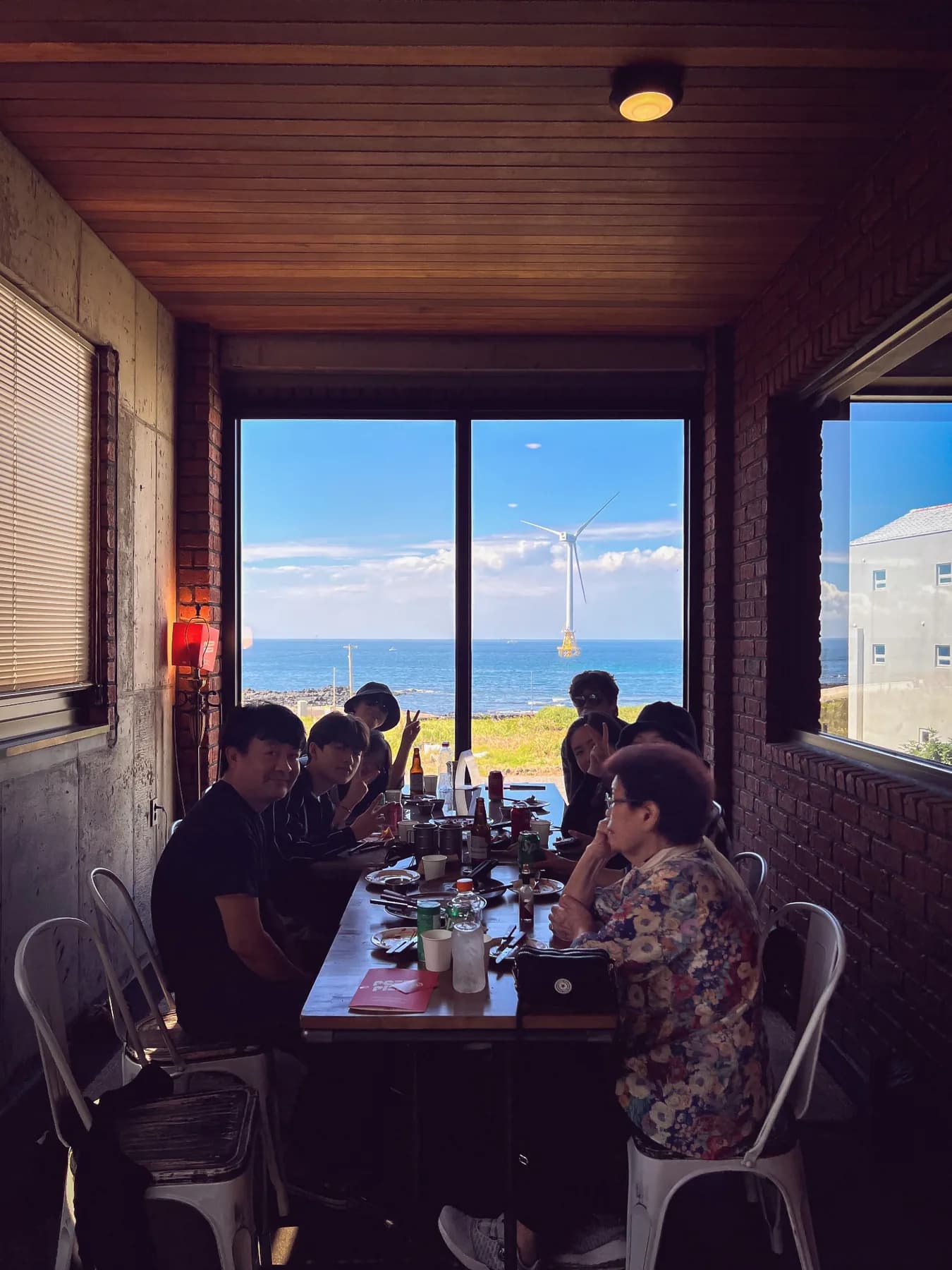 바다가 보이는 창가의 긴 테이블에 앉은 사람들