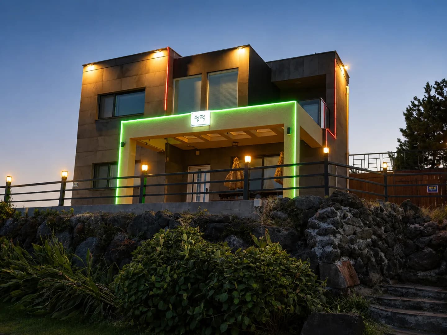 The exterior of the Witch’s Hill Jeju stay lit in the evening