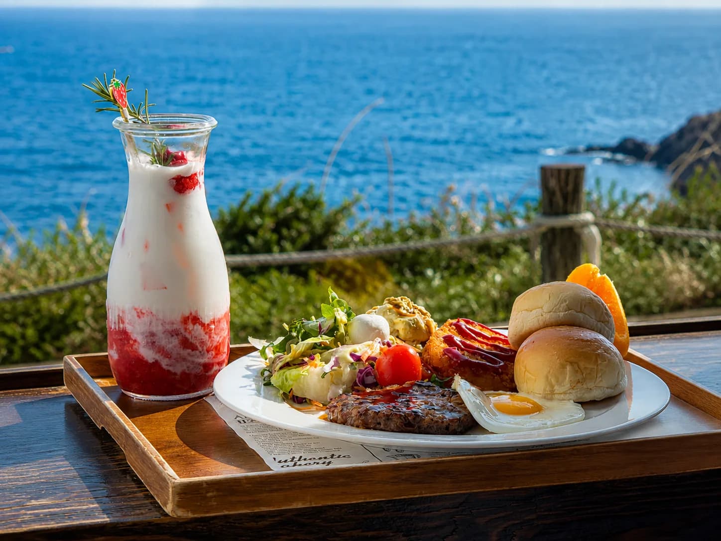 A brunch tray and drinks on a table beside the Jeju coast