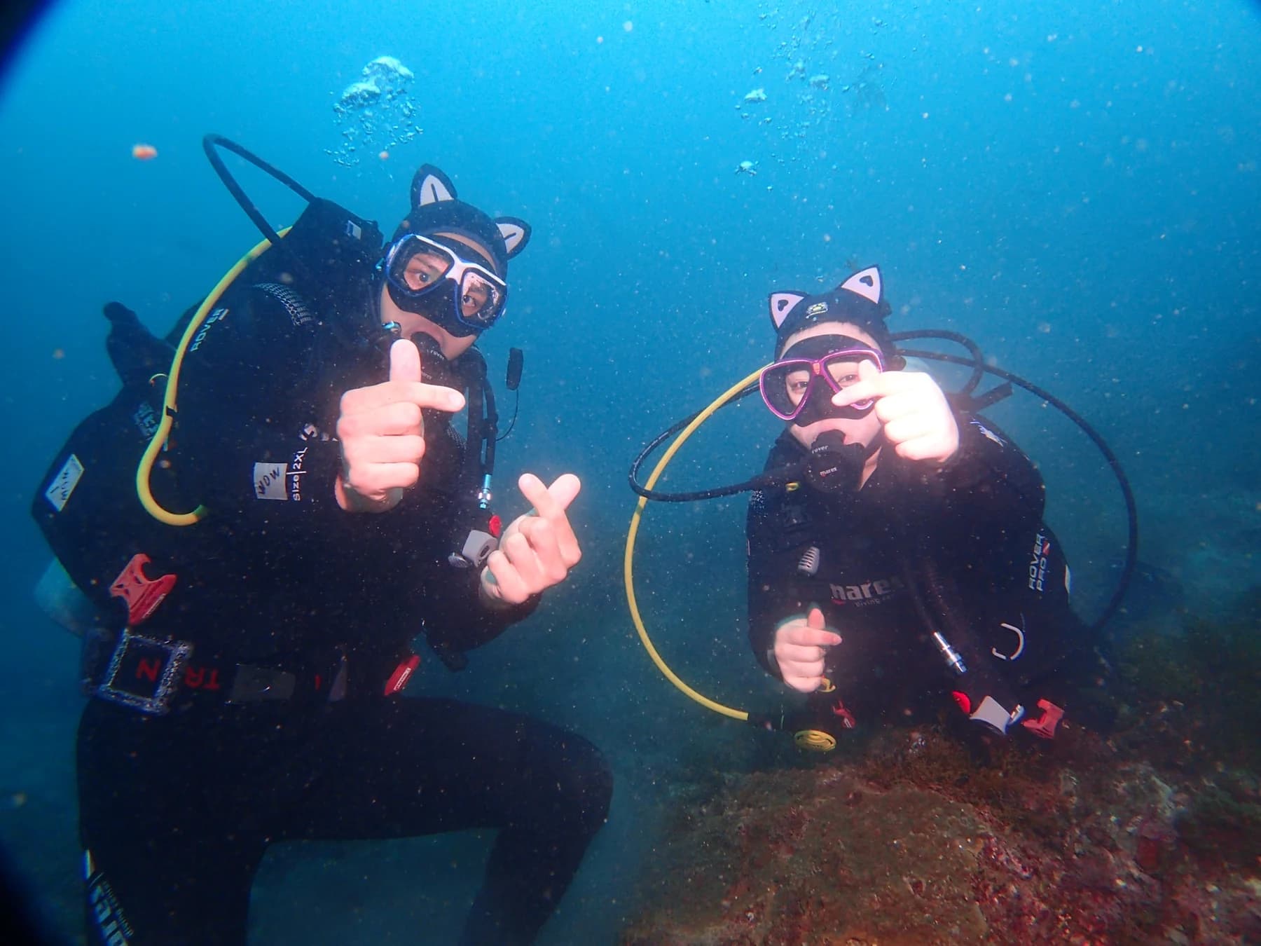 Two divers checking hand signals underwater near Munseom