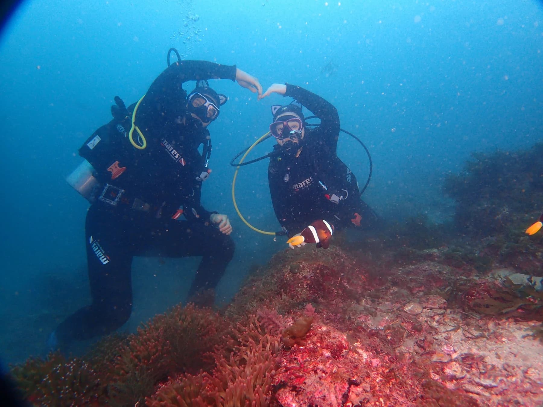 Two divers making a heart shape underwater near Munseom