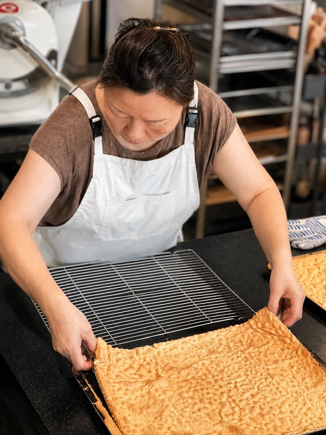 Lee Kyungsoon checking bread on a baking sheet