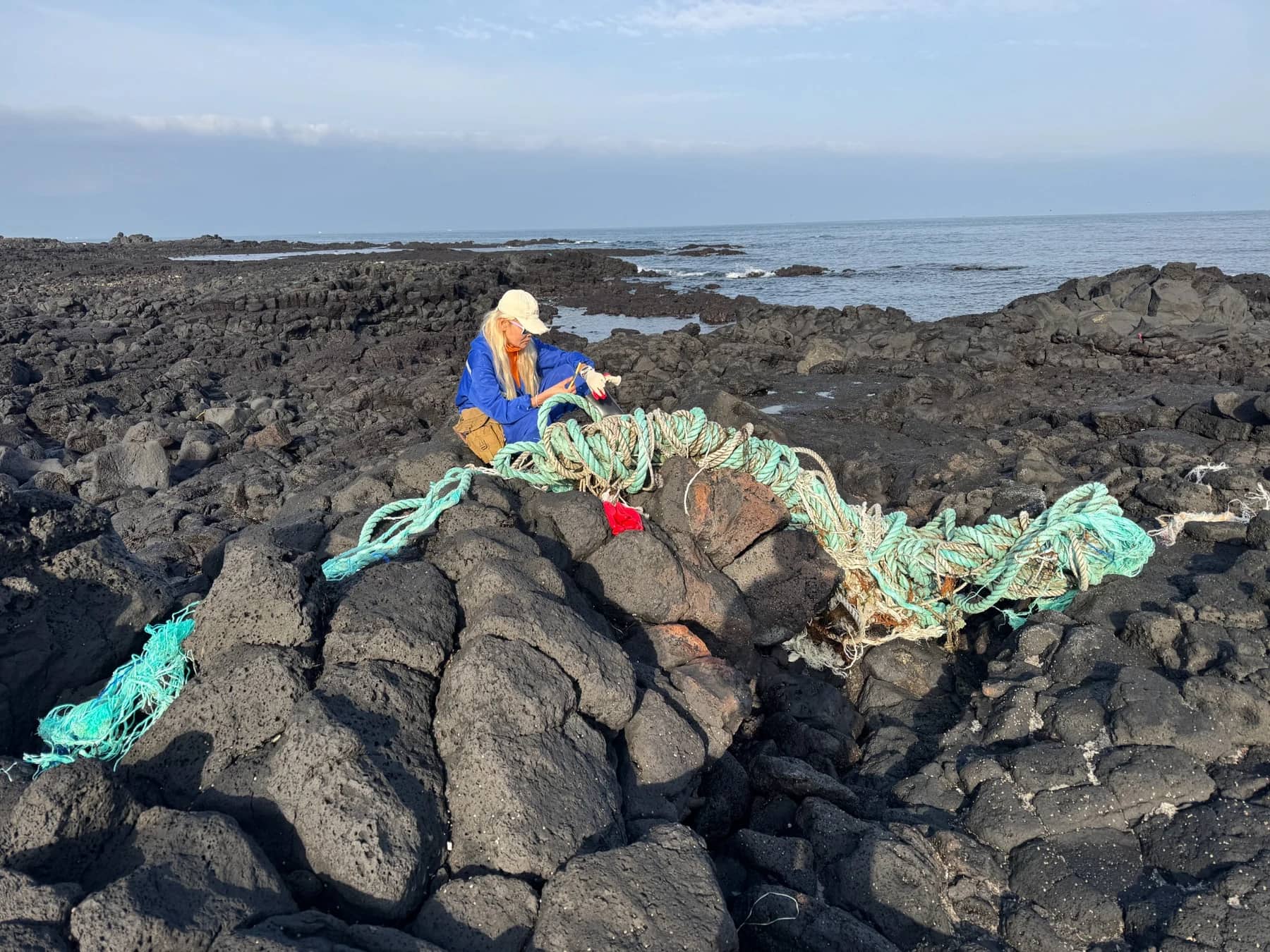 Seol Jinmi removing a large discarded rope from Jeju's volcanic coast