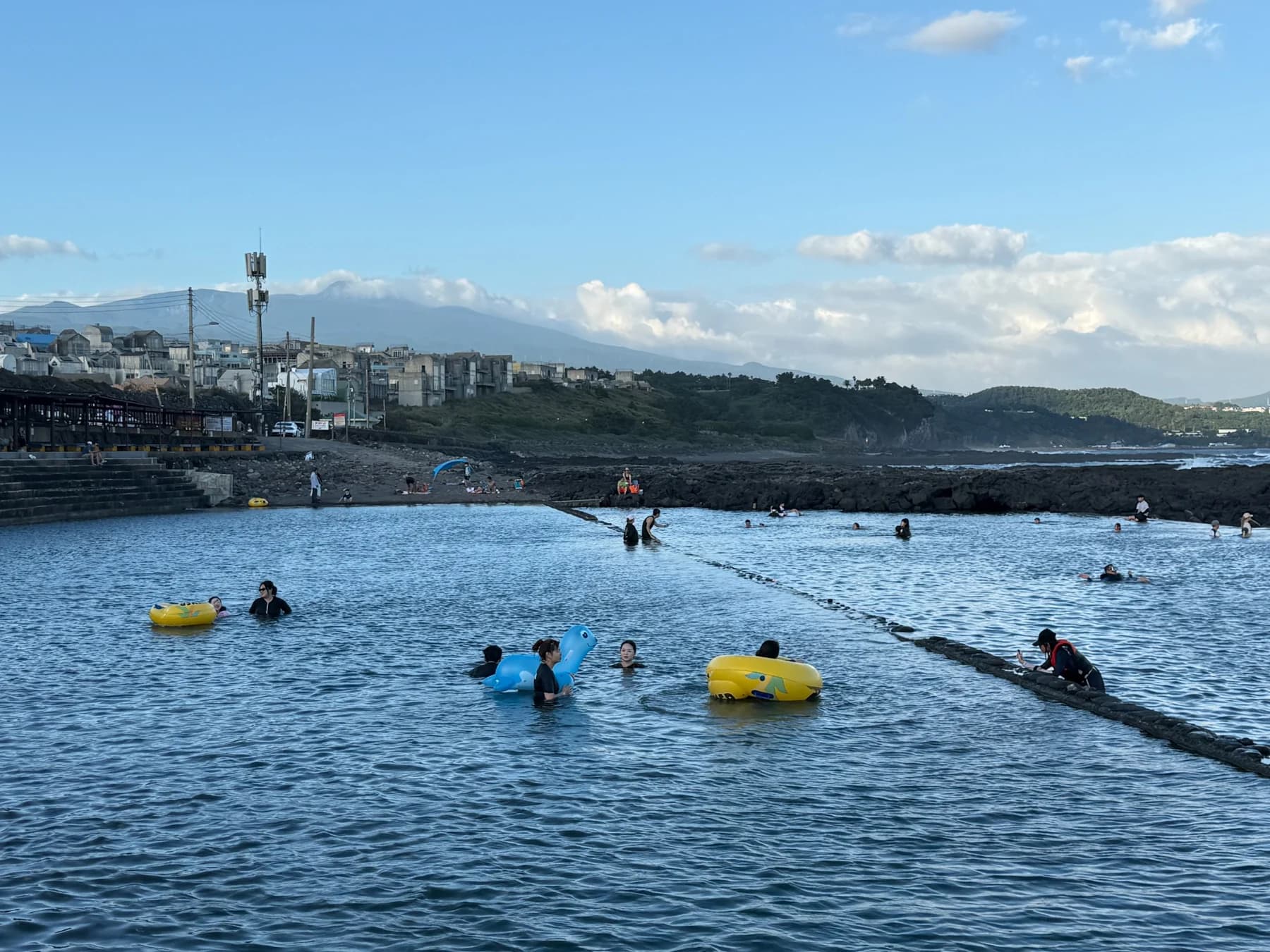 People swimming at Nonjitmul with Hallasan and the village behind them