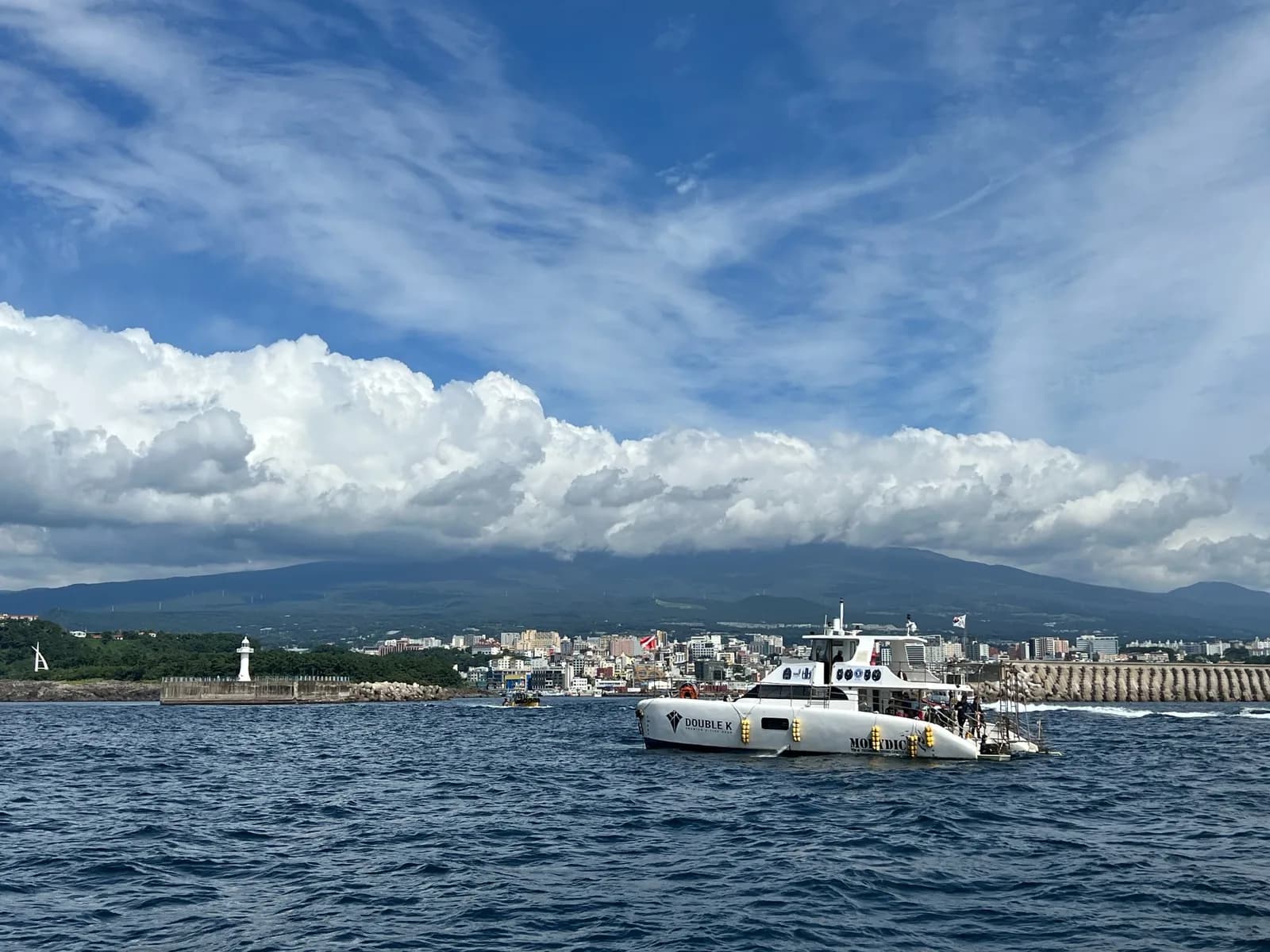 Seogwipo city and inland mountains seen beyond a dive boat at sea