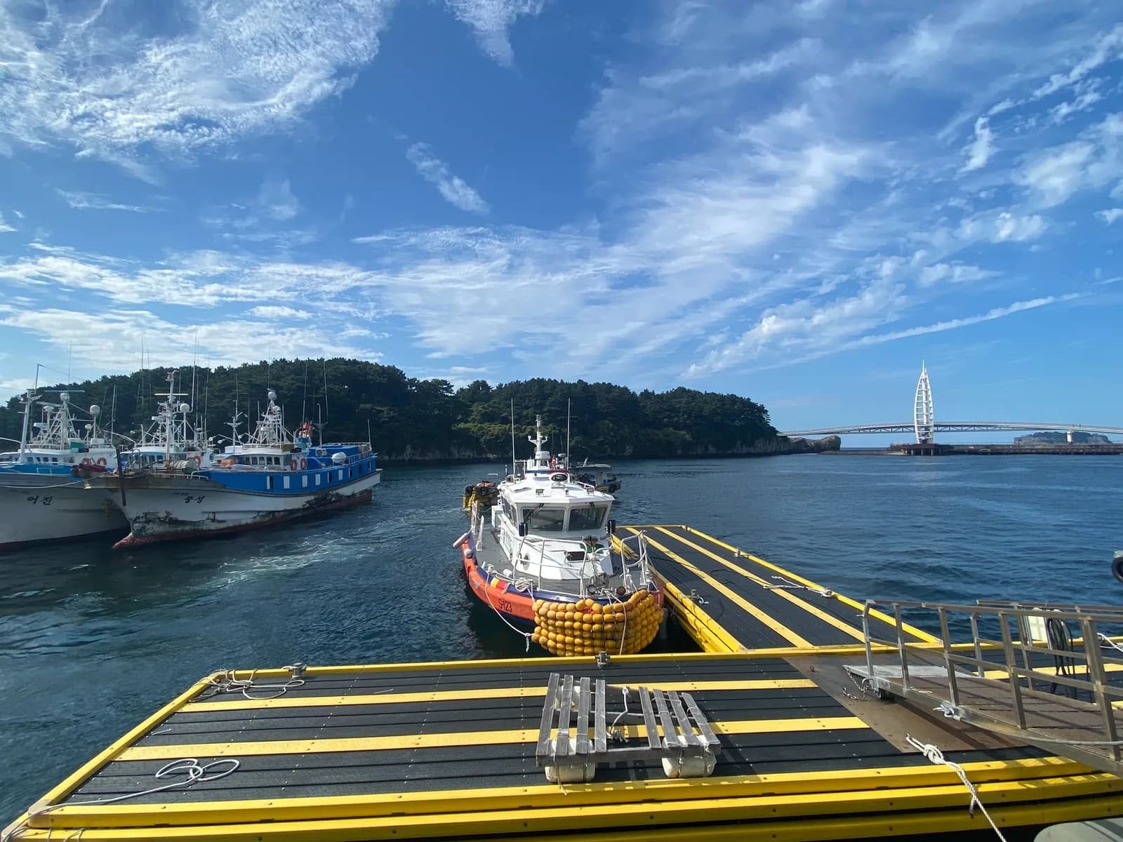 Boats moored at Seogwipo Port with Saeyeongyo Bridge in the distance