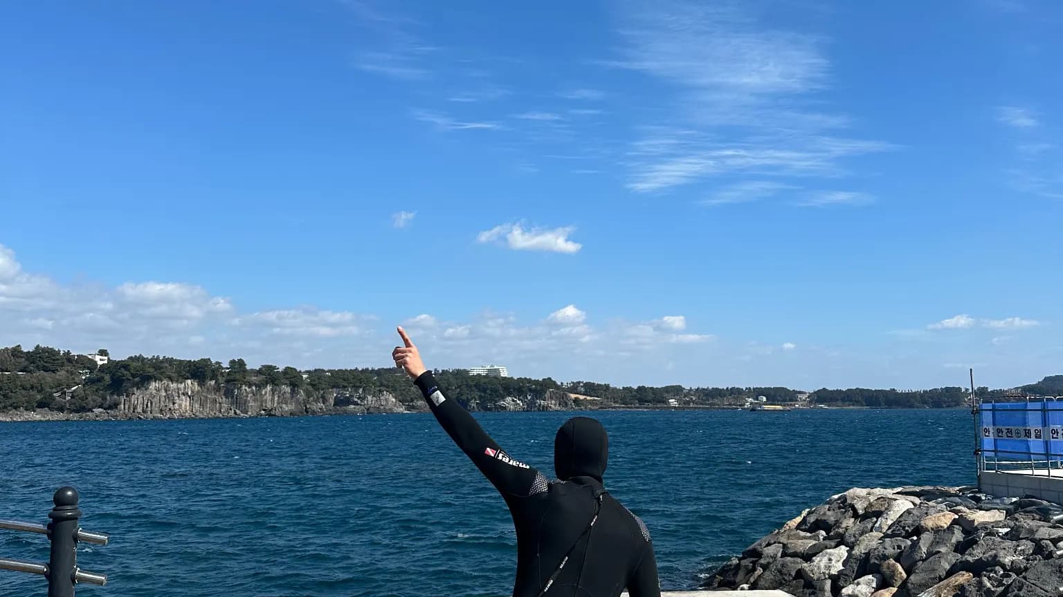 A diver looking across the blue sea and coast at Seogwipo Port